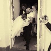 fotoreportaż ślubny: pan młody wnosi panne młodą przez drzwi