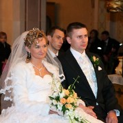 fotografia ślubna przedstawia państwa młodych siedząch w kościele